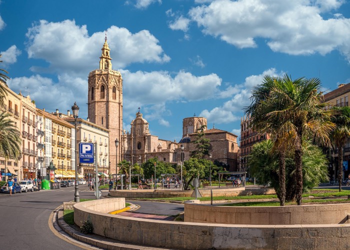 Vue de la cathédrale de Valence et du Miguelete sur une place animée au cœur de la ville, sous un ciel bleu méditerranéen.